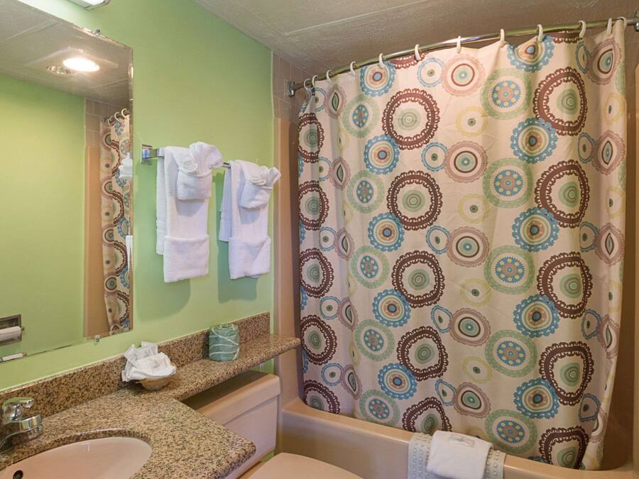 A bathroom with a sink, mirror, and shower curtain.
