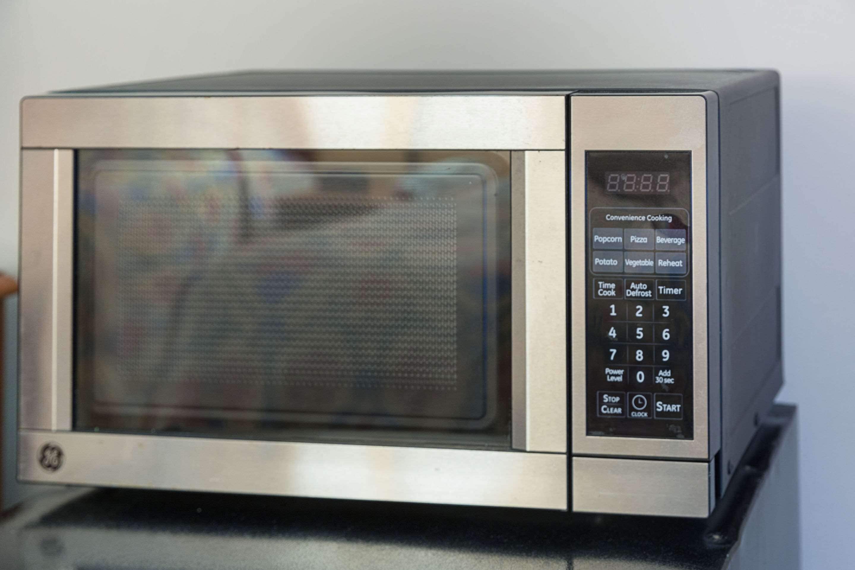 A stainless steel microwave with a digital display and a keypad.