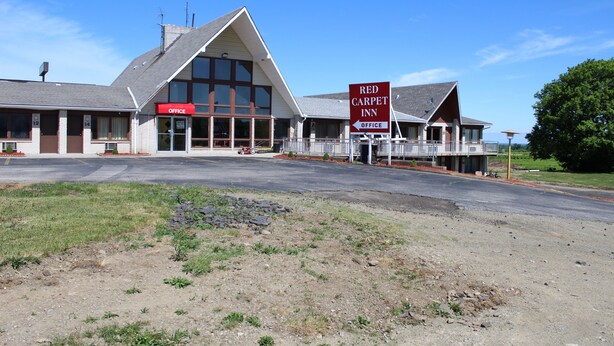 A Red Carpet Inn with a prominent office sign, a large glass facade, and a spacious parking area. -  Grapevine Inn (North East)