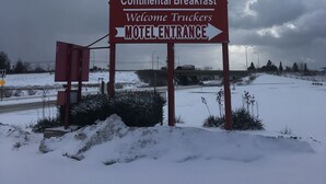 A motel sign with a Red Carpet Inn logo, indicating low rates, free HBO, 24/7 open, continental breakfast, and welcoming truckers. -  Grapevine Inn (North East)