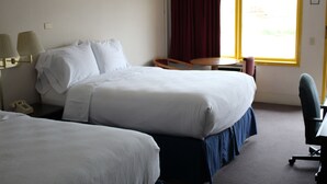 A hotel room with two beds, a desk, a chair, a lamp, and a window with curtains. -  Grapevine Inn (North East)