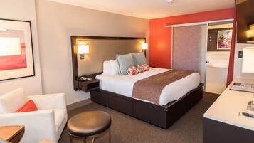 A modern hotel room with a large bed, bedside lamps, a desk, and a chair.