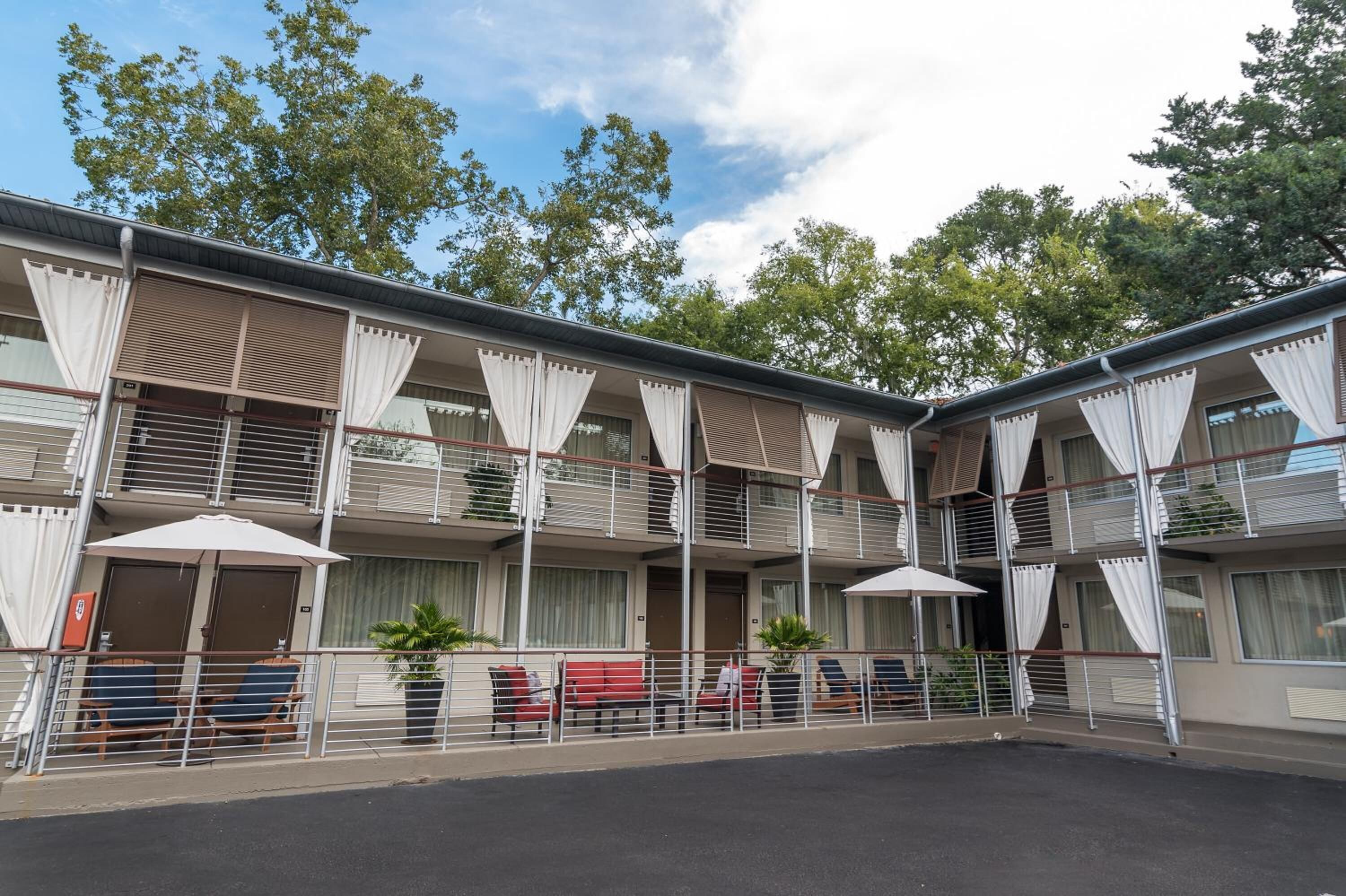 Un hôtel à plusieurs étages doté de balcons, d’un espace extérieur aménagé et de plantes en pot.