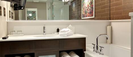 Un baño moderno con un espejo grande, una bañera y un mueble de tocador con repisas para toallas.