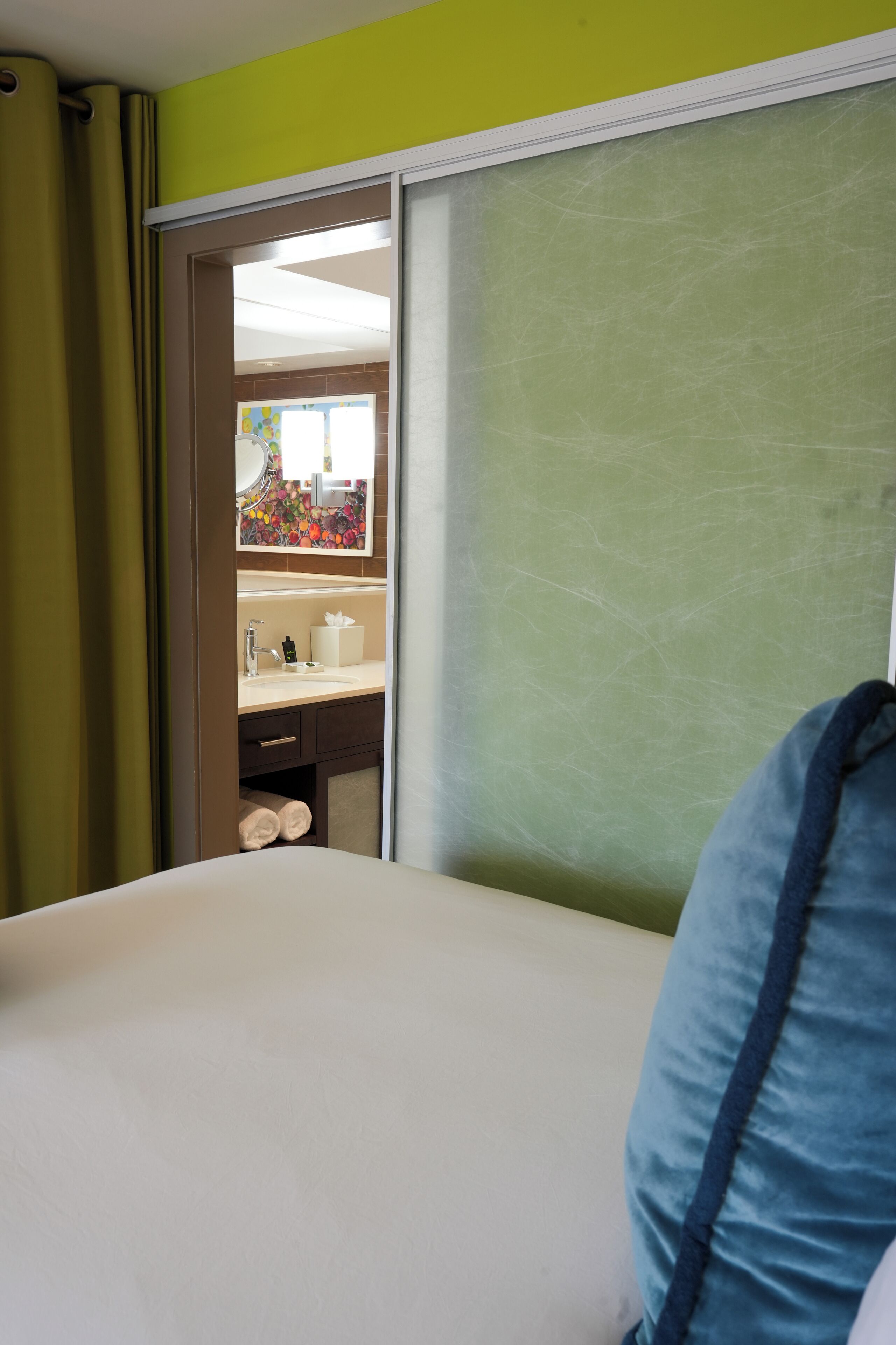 Een hotelkamer met een bed, een badkamer met een wastafel en een spiegel.