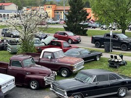 A parking lot with various vehicles including a maroon truck, a black sedan, and a red SUV.