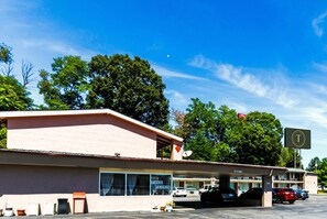 Un motel con un letrero grande, un estacionamiento y un edificio de techo plano.