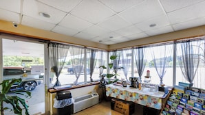 A room with a large window, a table with a floral tablecloth, and a display of books. - Edyn Hotel By Townhouse Wytheville US 52 (Wytheville)