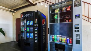 Two vending machines, one Pepsi and one Coca-Cola, in a hallway with a concrete floor and a metal staircase. - Edyn Hotel By Townhouse Wytheville US 52 (Wytheville)