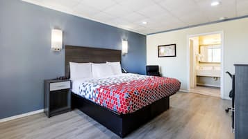 Habitación de hotel moderna con una cama grande, mesitas de noche, un escritorio y un baño visible a través de una puerta abierta.