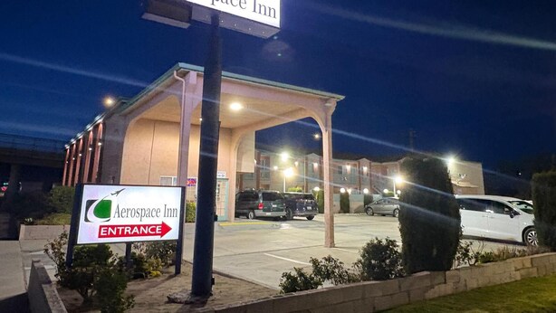 An exterior view of the Aerospace Inn with a prominent entrance sign and a covered parking area.
