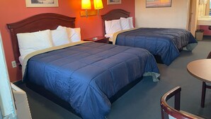 A hotel room with two beds, a desk, a chair, and a small table.