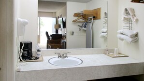 A bathroom with a sink, mirror, and towel rack. - American Inn and Suites (Jasper)