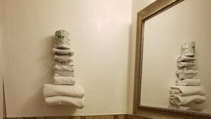 A bathroom with a toilet, sink, and stacked towels on the wall.