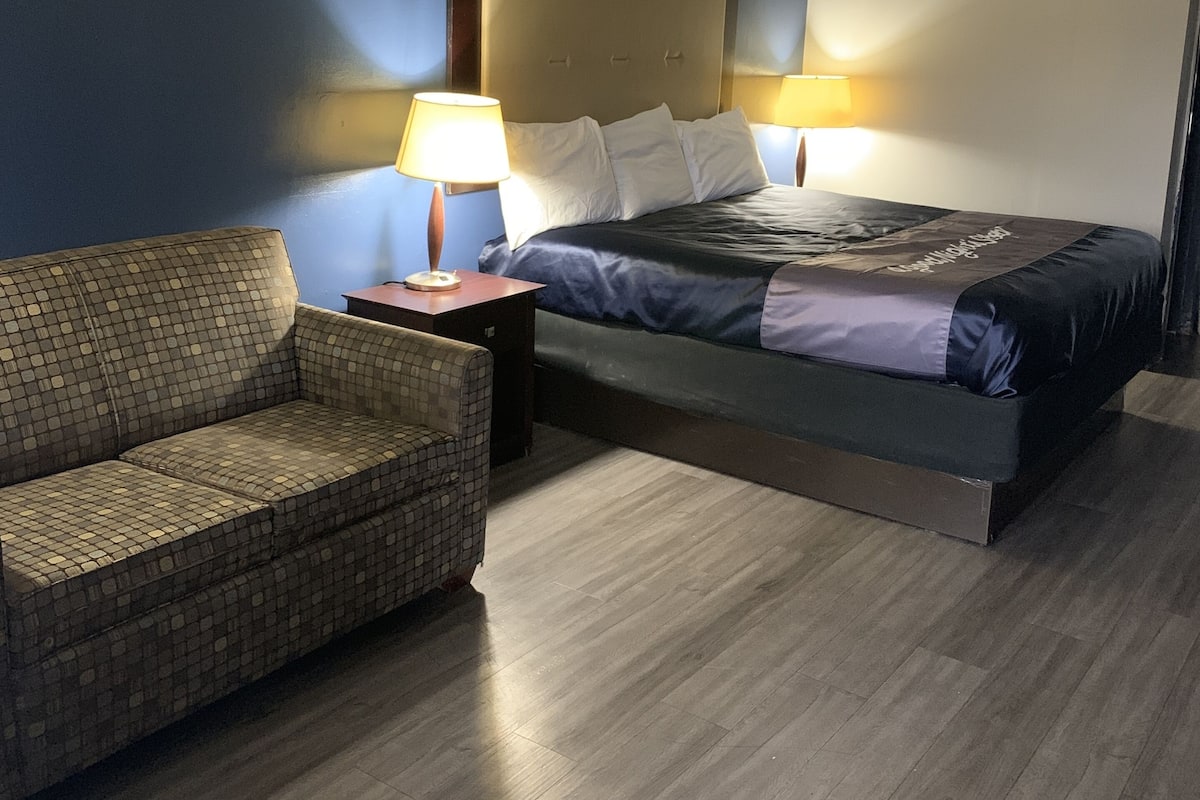 A hotel room with a bed, a chair, and two bedside lamps.