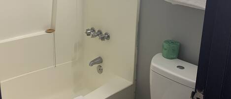 A bathroom with a bathtub, toilet, and a towel rack.