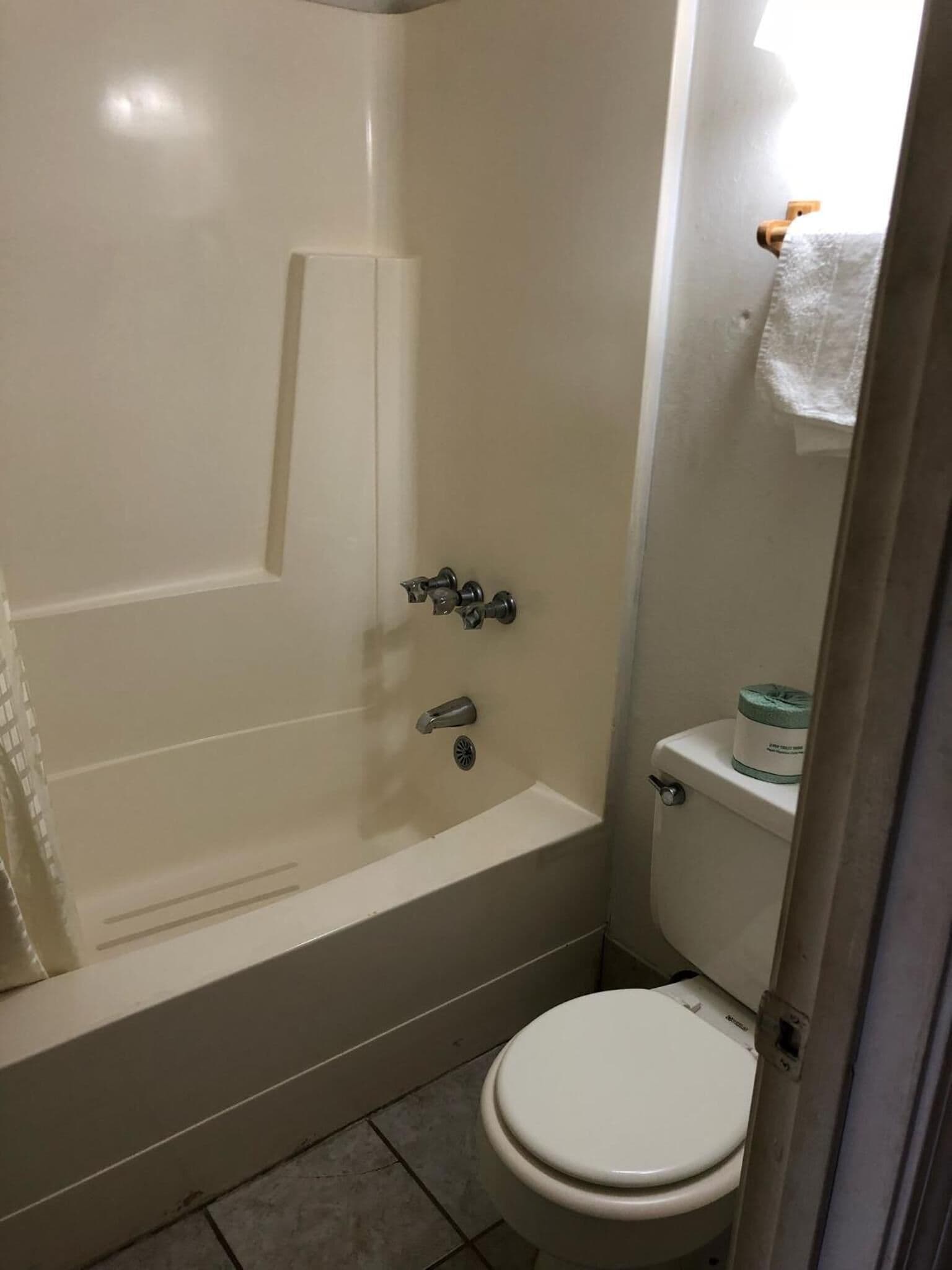 Une petite salle de bain avec une baignoire, des toilettes et un porte-serviettes.
