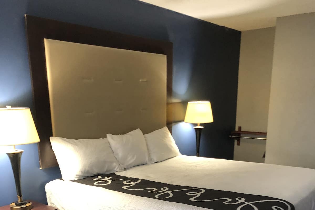 A hotel room with a large bed, two bedside tables, and two wall-mounted lamps.