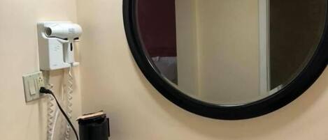 A bathroom with a sink, mirror, and hairdryer.