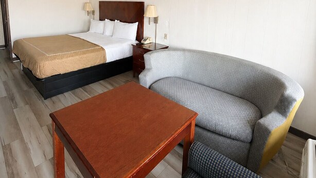 Une chambre d’hôtel avec un lit, un canapé, une table et une lampe.
