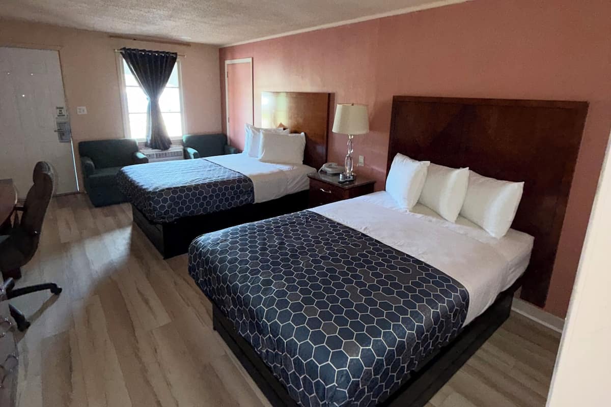 A hotel room with two beds, a desk, and a chair.