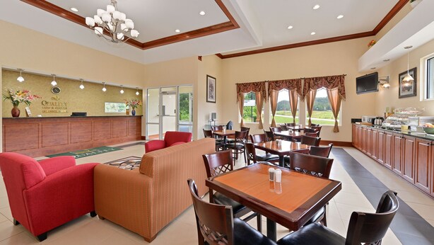 A hotel lobby with a reception desk, seating area, dining tables, and a buffet. - Quality Inn & Suites Cartersville North (White)