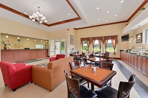 Eine Hotelhalle mit Empfangstresen, Sitzgelegenheiten, Esstischen und einem Buffet.