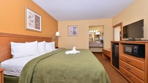 A hotel room with a bed, a television, a microwave, and a dresser. - Quality Inn & Suites Cartersville North (White)