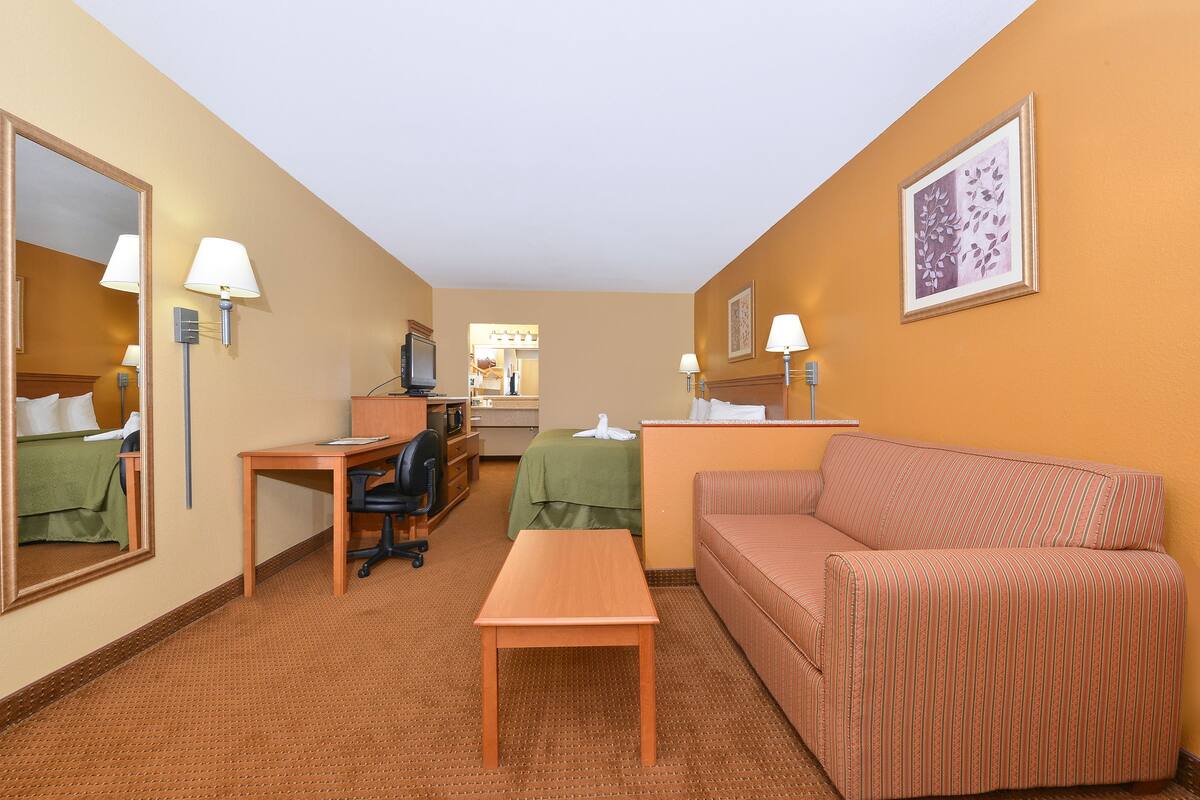 Une chambre d’hôtel équipée d’un lit, d’un bureau, d’une chaise, d’un canapé et d’une télévision.