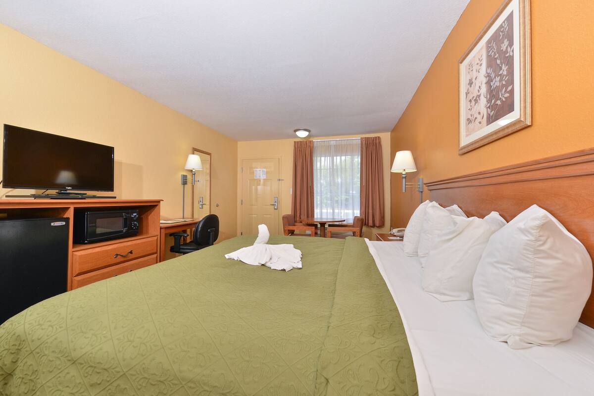 Une chambre d’hôtel équipée d’un lit, d’une télévision, d’un four à micro-ondes, d’un bureau et d’une chaise.
