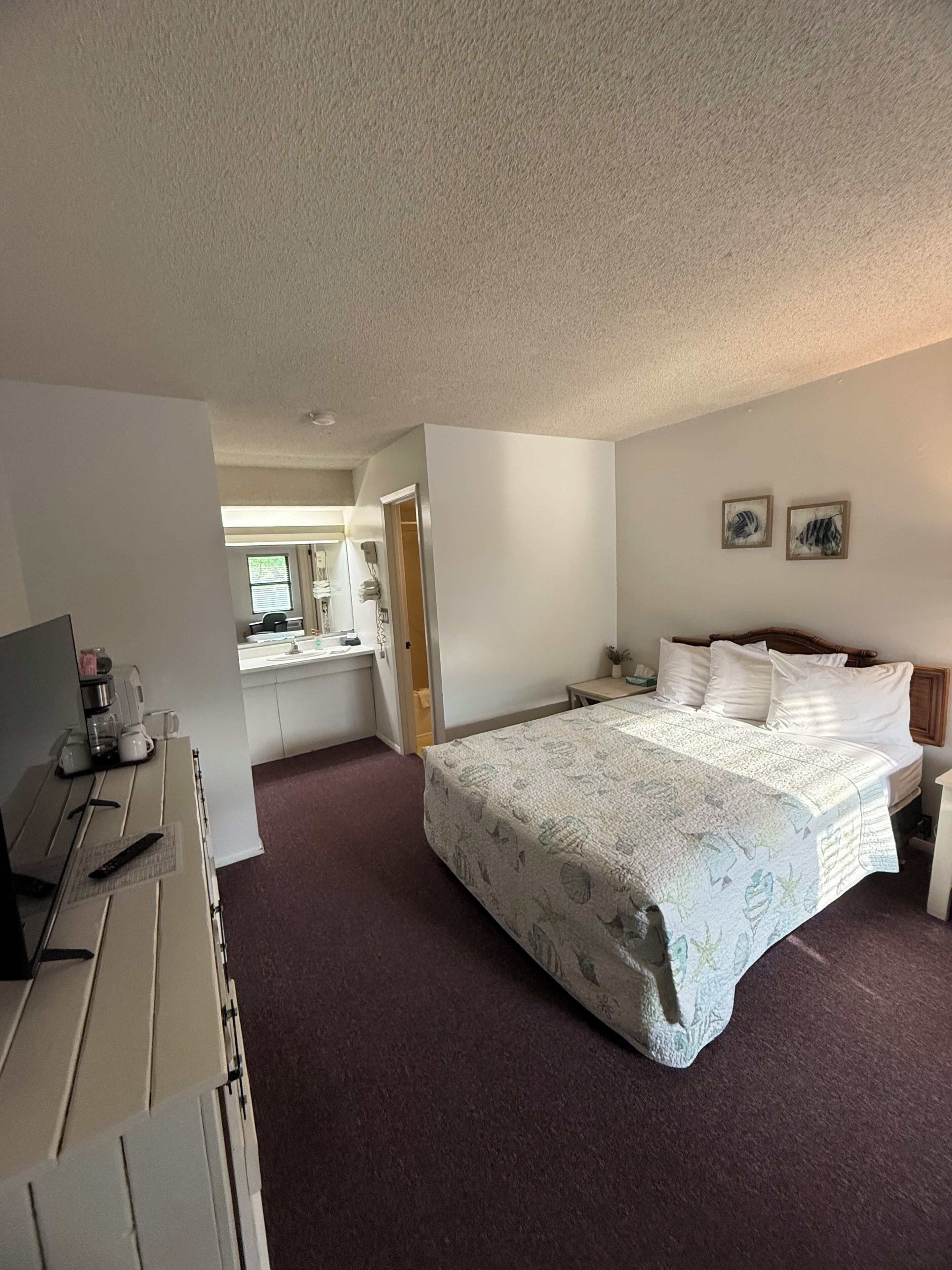 Una habitación de hotel con cama, escritorio y kitchenette.