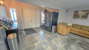 A living room with a sofa, a trash bin, a door, and a refrigerator. - The No Wake Inn - Osage Beach (Osage Beach)