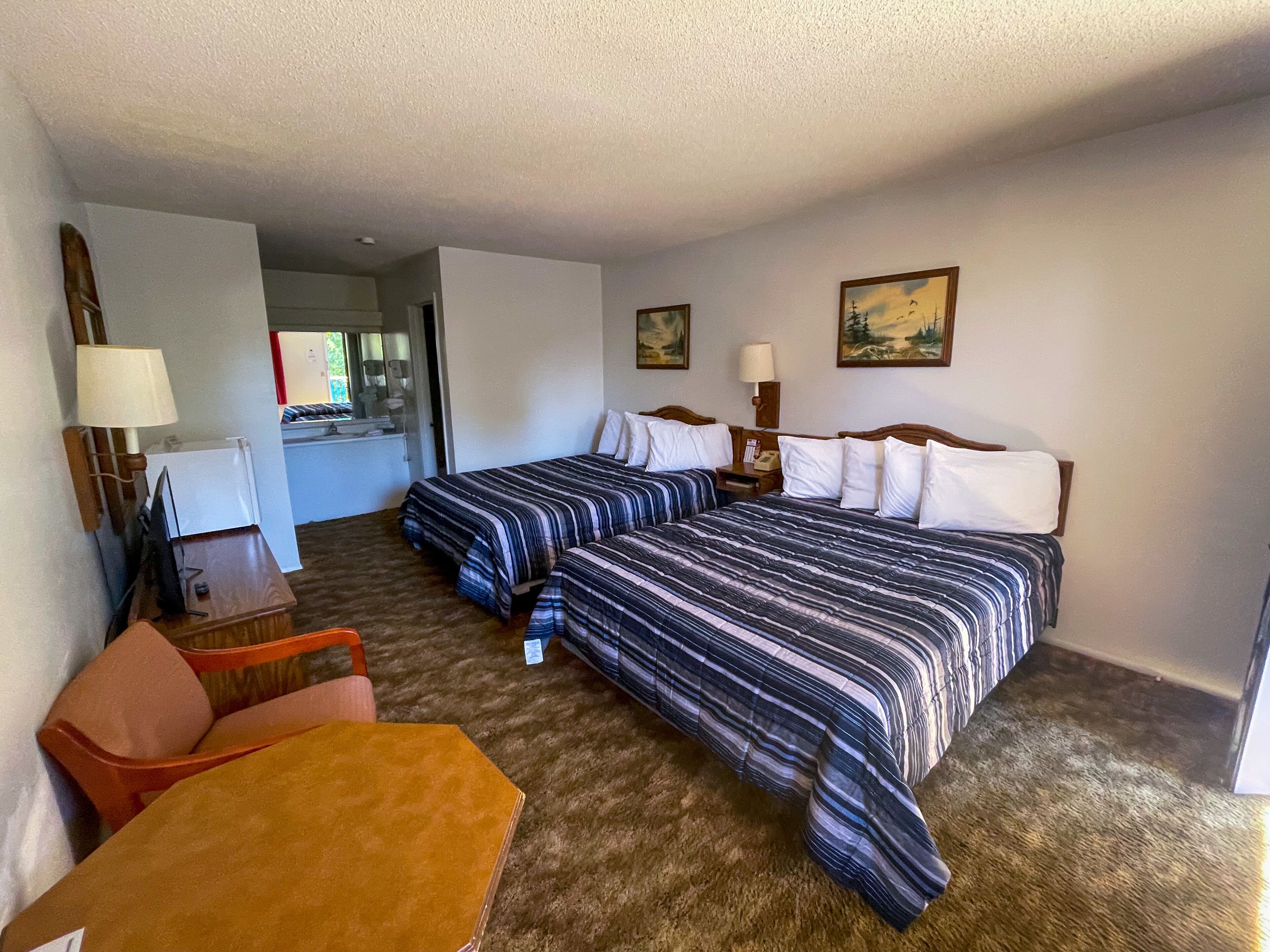 Une chambre d’hôtel avec deux lits, un bureau, une chaise et une petite table.