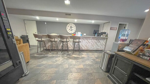 A reception area with a marble counter, bar stools, a clock, and a water dispenser. - The No Wake Inn - Osage Beach (Osage Beach)