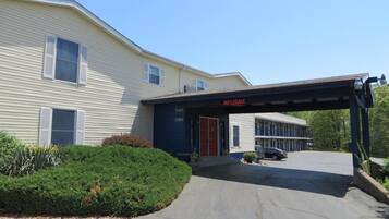 A motel with a covered entrance, numbered units, and a parking area.
