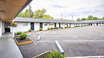 A motel with a row of rooms, a parking lot, and small planters with flowers.