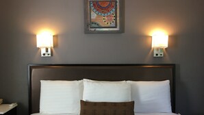 A hotel room with a large bed, two wall-mounted lights, and a decorative wall hanging. - Scottish Inns Milford (Milford)