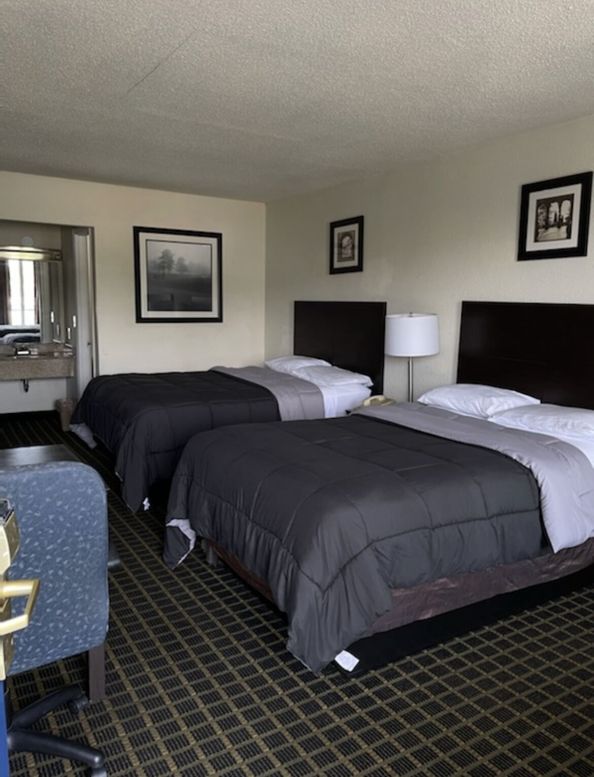 Une chambre d’hôtel avec deux lits, un bureau, une chaise et un miroir.