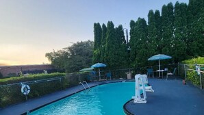 Una piscina con cubierta azul, rodeada por una cerca y protegida por sombrillas.
