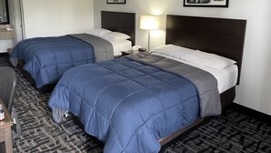 Habitación de hotel con dos camas, un escritorio y una silla. En la pared, se observan cuadros enmarcados.