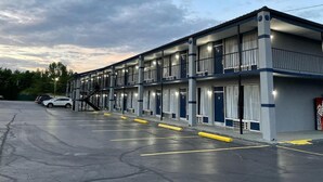 Un motel de varios pisos con un estacionamiento al frente.