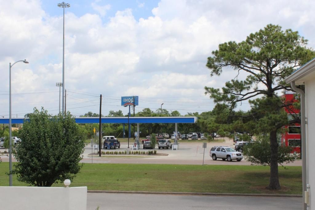 A gas station with a blue canopy, multiple fuel pumps, and a parking lot with cars.