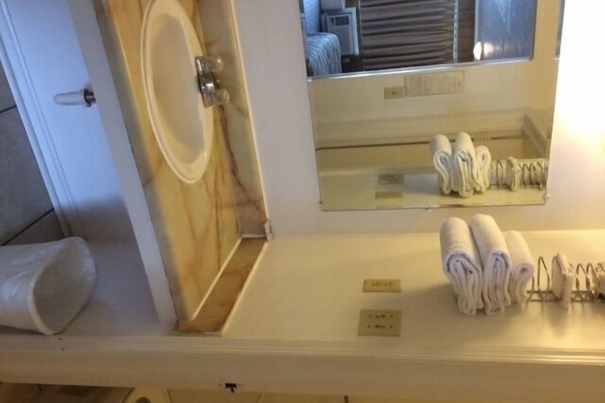 A bathroom with a sink, mirror, and towel rack.