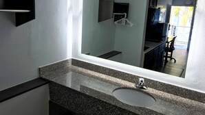 A bathroom with a granite countertop, a white sink, and a large mirror.