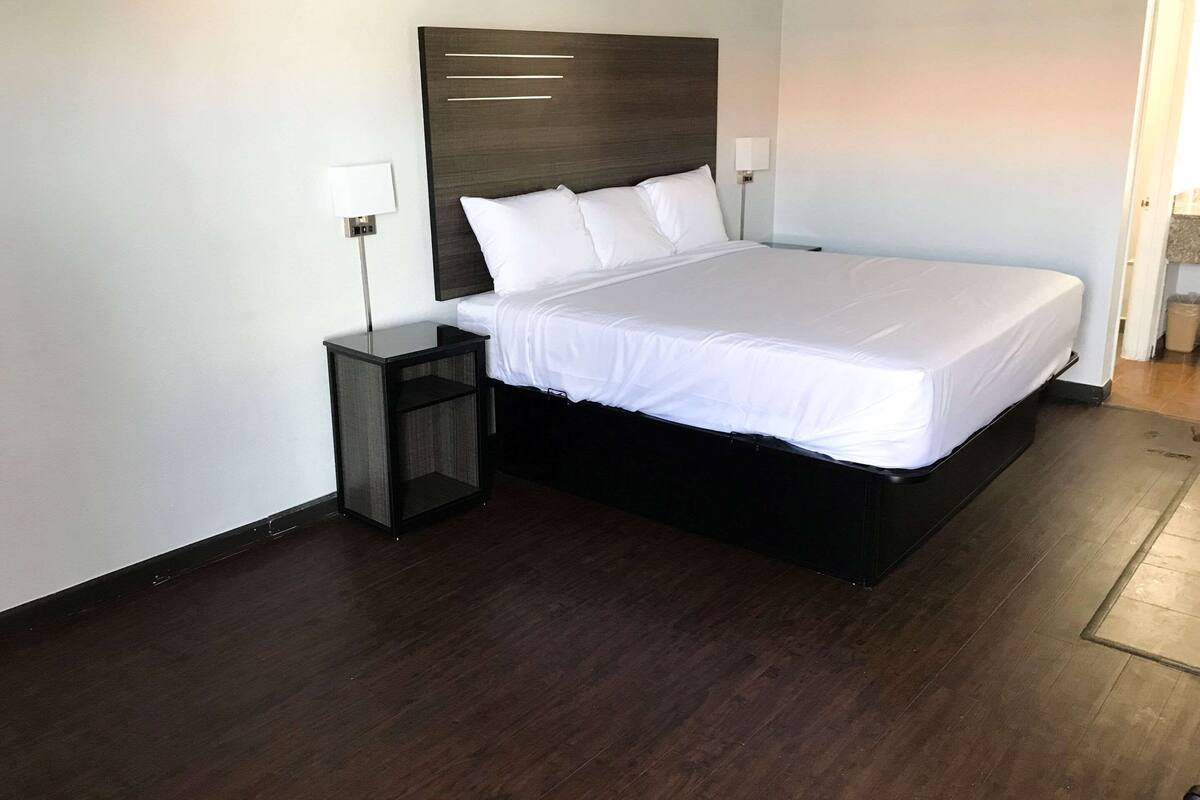 A modern hotel room with a large bed, a bedside table, and a nightstand.