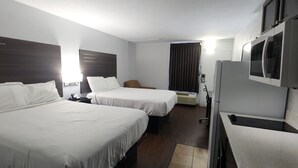 A hotel room with two beds, a desk, a chair, a microwave, and a refrigerator.