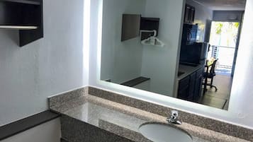 Un baño con un espejo grande, una encimera de granito y un lavamanos.