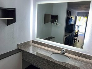 Un baño con un espejo grande, una encimera de granito y un lavamanos.