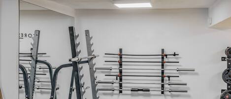 A gym with weightlifting equipment, a bench, and a kettlebell.