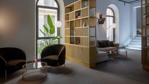 Una sala moderna con un sofá, sillones, una estantería y un ventanal grande.